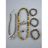 A GOOD ENSEMBLE OF TIGER'S EYE ADORNED DRESS JEWELLERY - a bead necklace, three bracelets, a