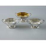 A TRIO OF OCTAGONAL BASED SILVER SALT CELLARS, boat shaped with twin handles and reeded