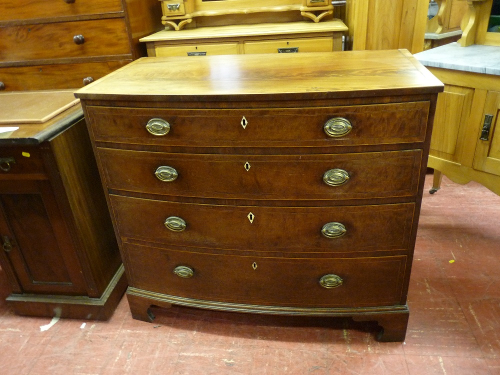 A REGENCY INLAID MAHOGANY BOW FRONT CHEST of four long drawers with oval backplates and swing