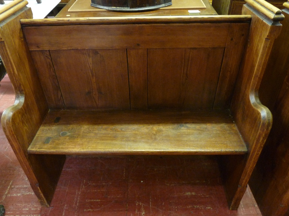 A PITCH PINE CHURCH PEW neatly proportioned with sloping rear book rail and shaped front arms, 105