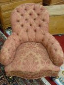 A VICTORIAN WALNUT FRAMED SALON ARMCHAIR, button upholstery with shaped seat front on turned front