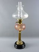 A VICTORIAN OIL LAMP with pink glass facet cut font on a classically styled brass column stand and
