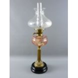 A VICTORIAN OIL LAMP with pink glass facet cut font on a classically styled brass column stand and
