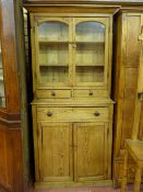 AN ANTIQUE STRIPPED PINE WELSH COUNTRY CUPBOARD, the inverted cornice over twin glazed arched top