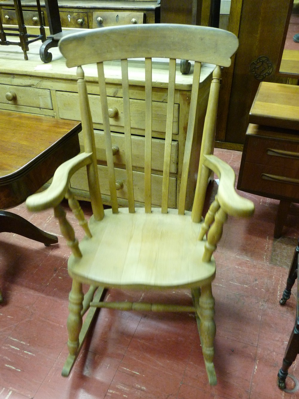 AN ANTIQUE STYLE FARMHOUSE ROCKING CHAIR with slatted back and turned arm and lower supports