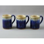 THREE ROYAL DOULTON STONEWARE MUGS with mottled green rim and raised heart decoration on a cobalt