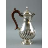 A CIRCULAR BASED SILVER COFFEE POT with swirled decoration and lion crest and having a composition