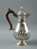 A CIRCULAR BASED SILVER COFFEE POT with swirled decoration and lion crest and having a composition