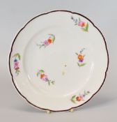 A NANTGARW PORCELAIN PLATE HAVING A CHOCOLATE ENAMELLED RIM, circa 1818, with a lobed and slightly