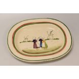 A LLANELLY POTTERY 'DUTCH GIRLS' PLATTER with red and green trim, the interior painted with a