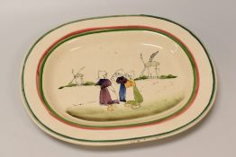 A LLANELLY POTTERY 'DUTCH GIRLS' PLATTER with red and green trim, the interior painted with a