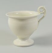 A SWANSEA PORCELAIN UNDECORATED CABINET CUP of urn shape with scrolling spurred handle, 9cms diam
