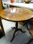 An antique oak tilt-top tripod occasional table