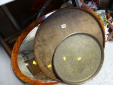 An oval framed mirror and a circular tray and a brass tray