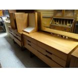 A vintage Uniflex lightwood bedroom suite comprising mirrored dressing table, chest of drawers,