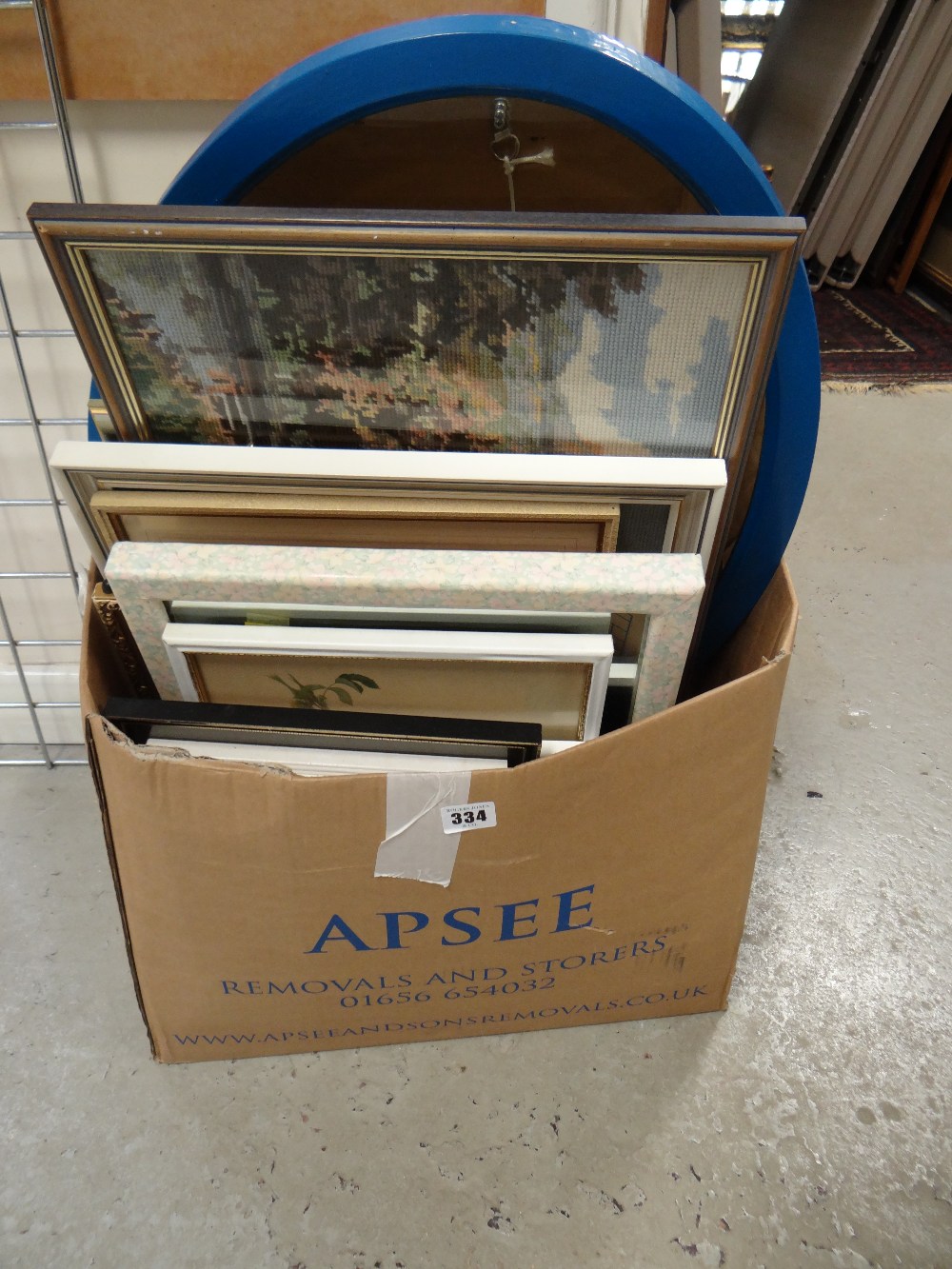A box of framed pictures and an oval mirror
