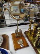 A vintage shaving mirror on a wooden platform base with cup hook shaving mug holder and blade