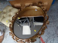 An oval framed mirror in a fancy gilt Rococo frame