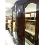 An Edwardian mahogany triple wardrobe with centre chest of four drawers and linen cupboard above