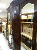 An Edwardian mahogany triple wardrobe with centre chest of four drawers and linen cupboard above