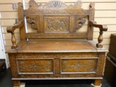 A VINTAGE CARVED OAK BOX SEAT HALL BENCH, the back with carved dragon's heads and floral panels,