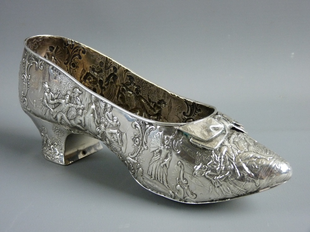 A CONTINENTAL SILVER MODEL OF A PERIOD STYLE SHOE with applied front bow and repousse style repeated