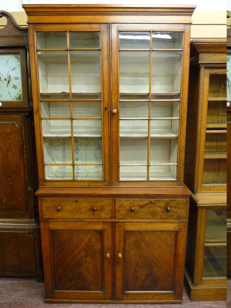 A GEORGE III MAHOGANY BOOKCASE CUPBOARD with shaped cornice over a twin section top, with ten