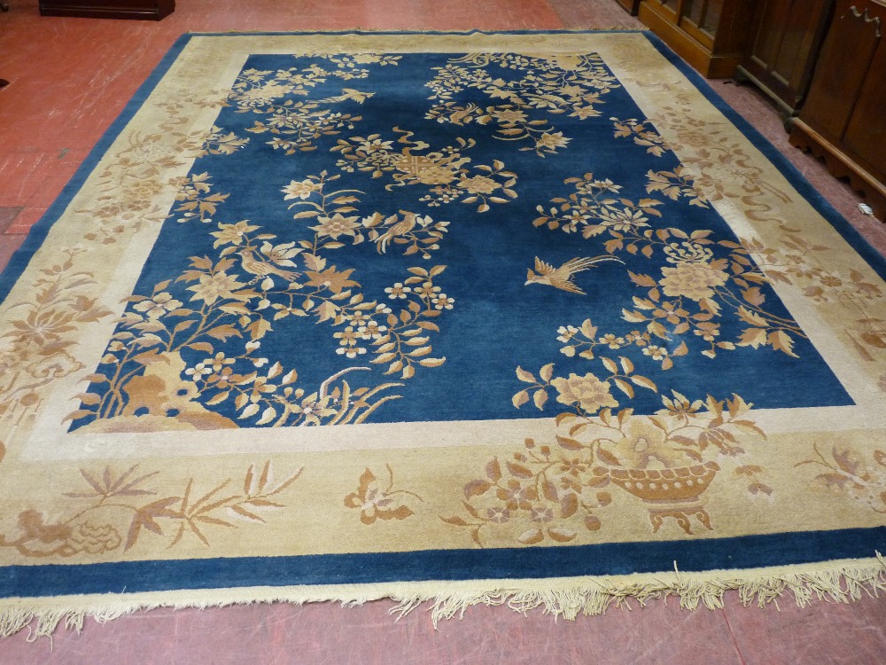 A LARGE ROOM SIZE RUG with a wide cream border on a blue ground, patterned with birds amongst