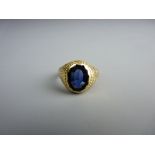 AN EIGHTEEN CARAT GOLD SIGNET RING with dark blue oval stone, 13 grms