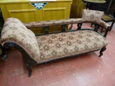 AN EDWARDIAN CHAISE LONGUE with pierced back rail and shaped supports on metal castors, the whole in