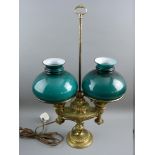 AN EMPIRE STYLE BRASS TABLE LAMP TWIN LIGHT with green glass shades on a relief decorated false