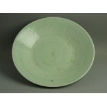 A LARGE GREEN CELADON DISHED CHARGER PLATE, 37 cms diameter