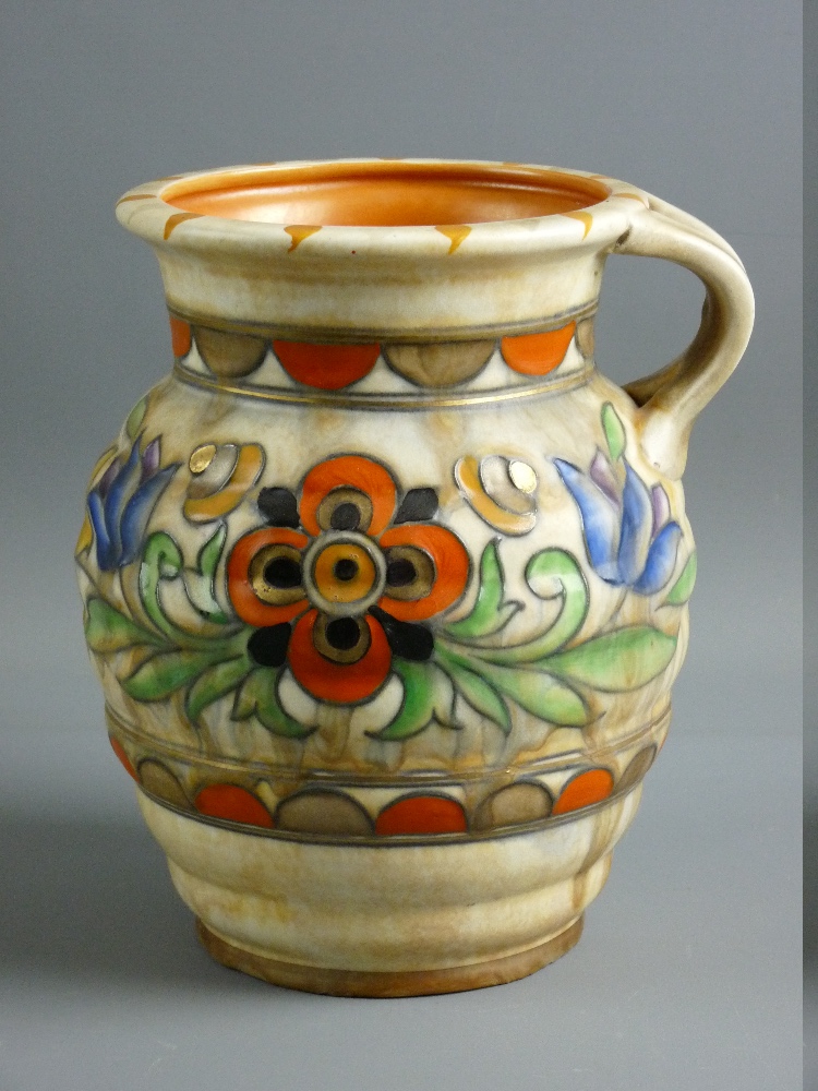 A CHARLOTTE RHEAD FOR CROWN DUCAL JUGS, tube lined decorated in colourful tones on a ribbed sand