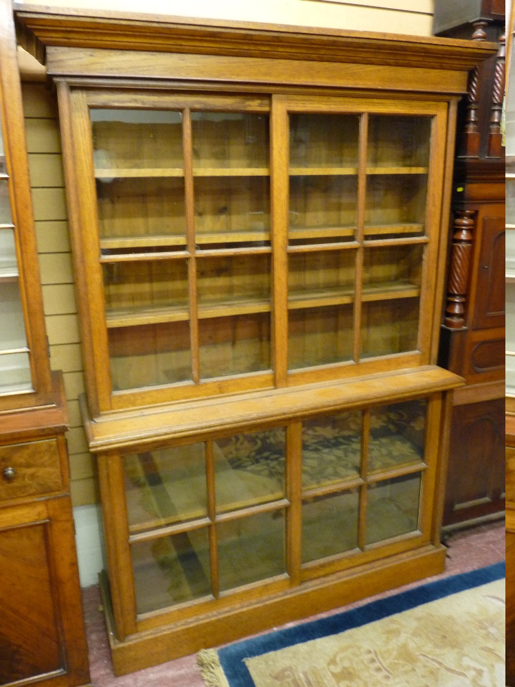 A CIRCA 1900 OAK BOOKCASE, the top section with inverted step cornice over twin glazed four panel