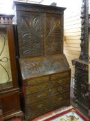 A HEAVILY CARVED OAK GEORGIAN BUREAU BOOKCASE, the top section with dentil cornice and fan carved