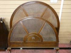 A WALNUT FRAMED BERGERE & IRON 4ft 6ins BED FRAME, the arched headboard with triple panelled cane