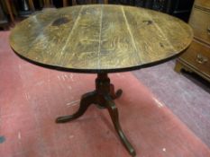 AN ANTIQUE OAK CIRCULAR TOPPED TABLE, the 84 cms diameter top on a turned column tripod base, 69.5