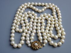 A DOUBLE NECKLACE OF SIMULATED PEARLS with fine garnet and pearl decorated circular nine carat