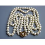 A DOUBLE NECKLACE OF SIMULATED PEARLS with fine garnet and pearl decorated circular nine carat