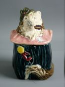 A CONTINENTAL MAJOLICA TOBACCO JAR in the form of a dog in costume with a pink ruff, 13 cms high,