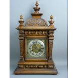 A WALNUT CASED ARCHITECTURAL STYLE MANTEL CLOCK, the silvered dial set with Roman numerals with