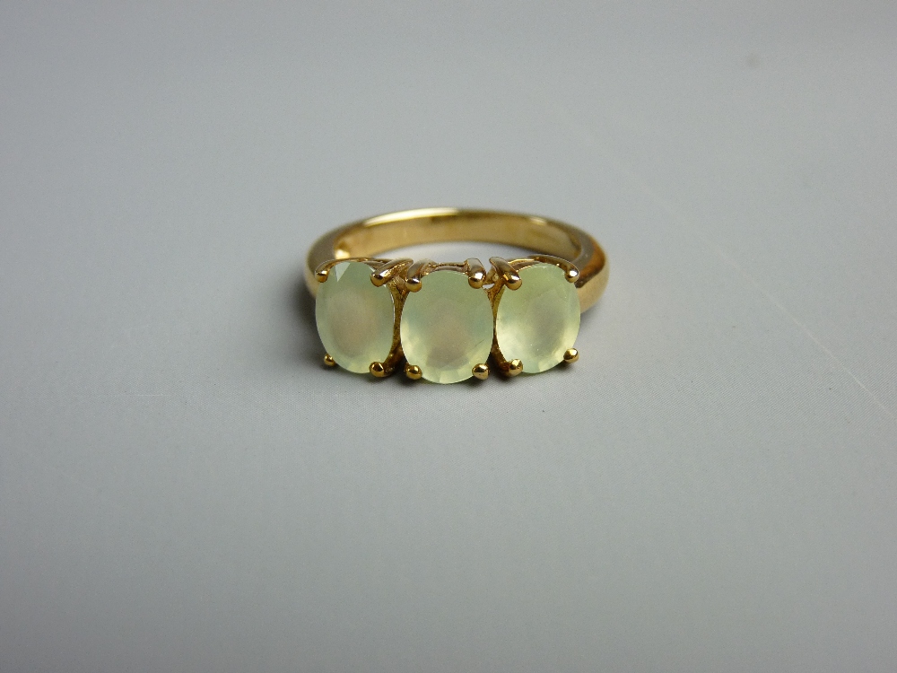 A NINE CARAT GOLD DRESS RING with three oval peridots, size 'N', 4 grms