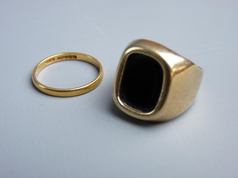 AN UNMARKED GOLD SIGNET RING with a dark agate stone, 6.2 grms gross and a twenty two carat gold