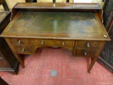 AN EDWARDIAN CROSSBANDED MAHOGANY WRITING DESK having a railback shelf with shaped ends above a