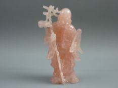 A CARVED ROSE QUARTZ FIGURE of a Chinese Immortal, the bearded standing figure holding a staff, 13