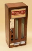 A VINTAGE CIGARETTE DISPENSER FOR WOODBINE in an oak case, 'INSERT 15p' with key (with staff for