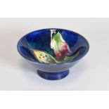 A MOORCROFT FOOTED DISH of blue ground with tube-lined flowers and leaves, 11cms diam