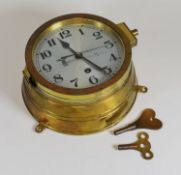 A KRIEGESMARINE SHIP'S BELL BULKHEAD CLOCK having a silver dial with Arabic numerals, 17cms diam