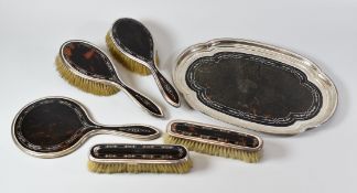 A TOROISESHELL & SILVER DRESSING-TABLE SET comprising four matching brushes, mirror and shaped tray,