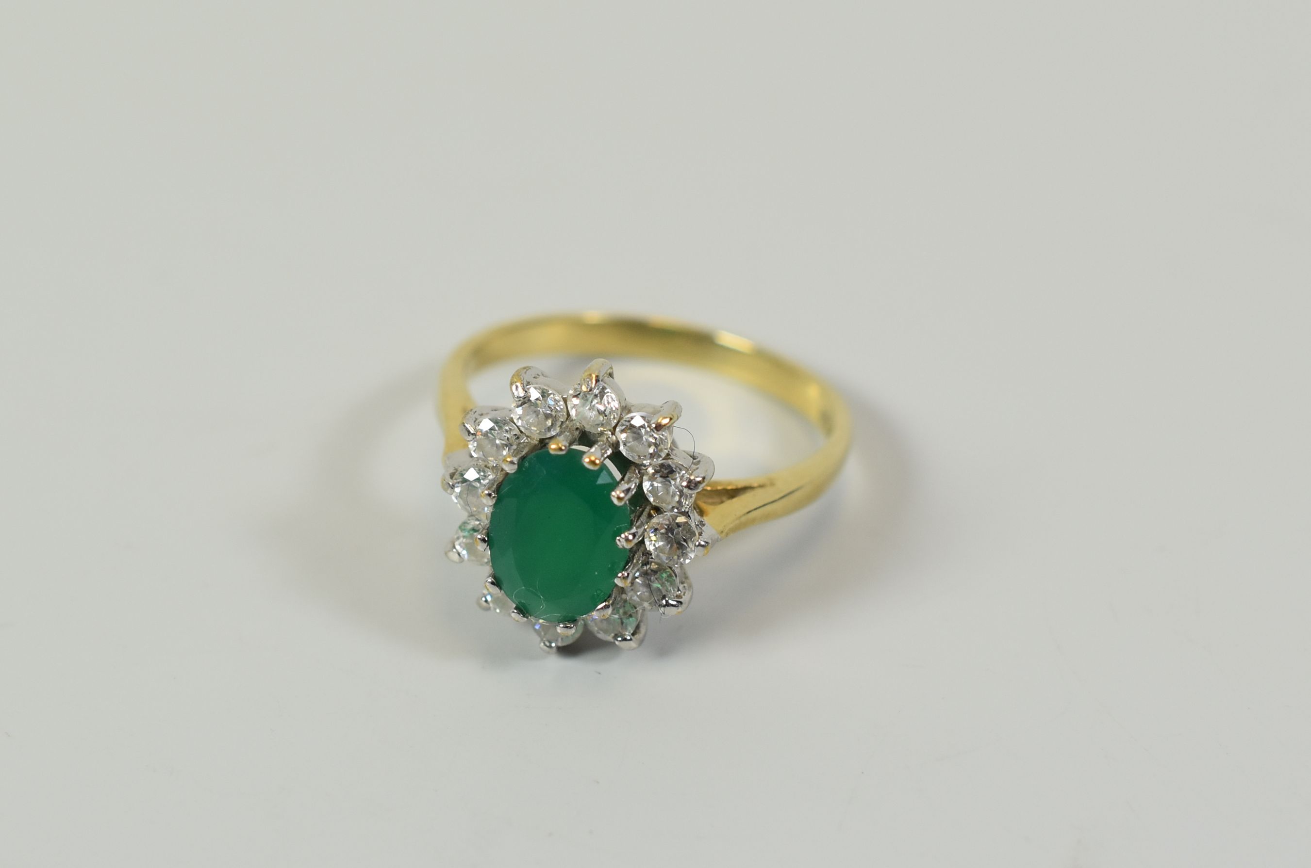 AN EMERALD & DIAMOND FLORAL RING, in 9ct yellow gold and composed of an oval emerald and twelve